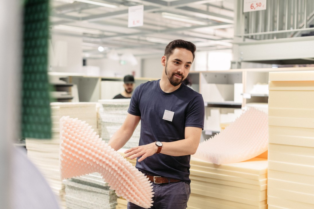 A Modulor employee holds a pink foam sheet in the stationery shop's spacious warehouse.