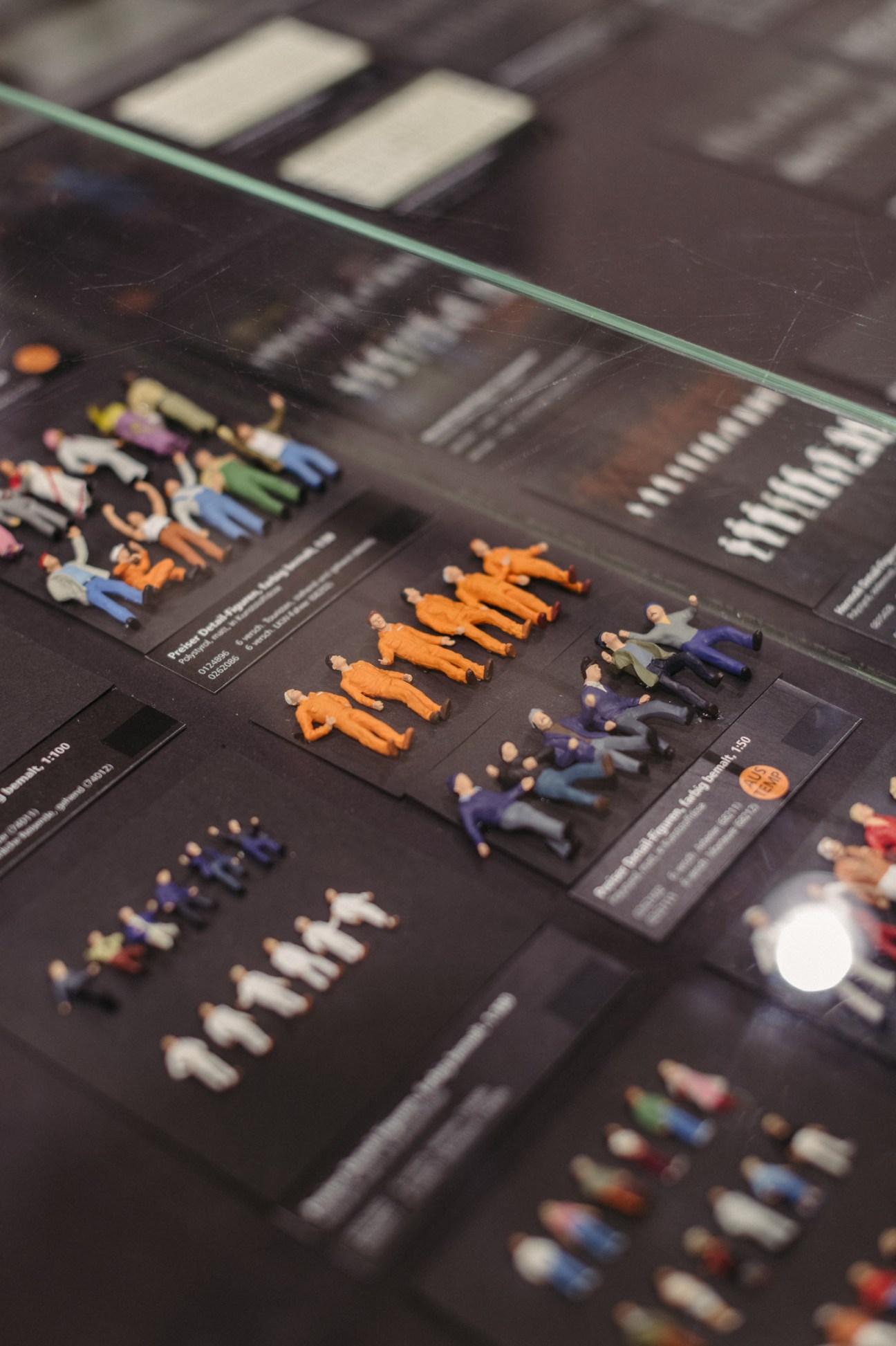Close-up of colorful foam rubber figures and architectural model materials displayed on a dark surface with product information cards.