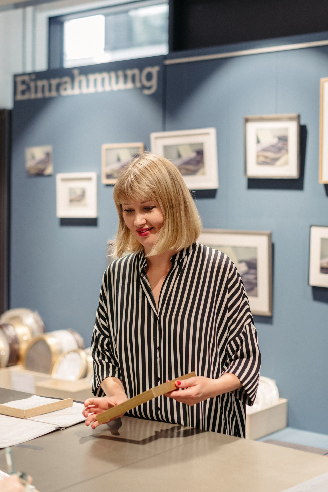 Woman in striped shirt examining framed artwork at Modulor stationery shop in Berlin.