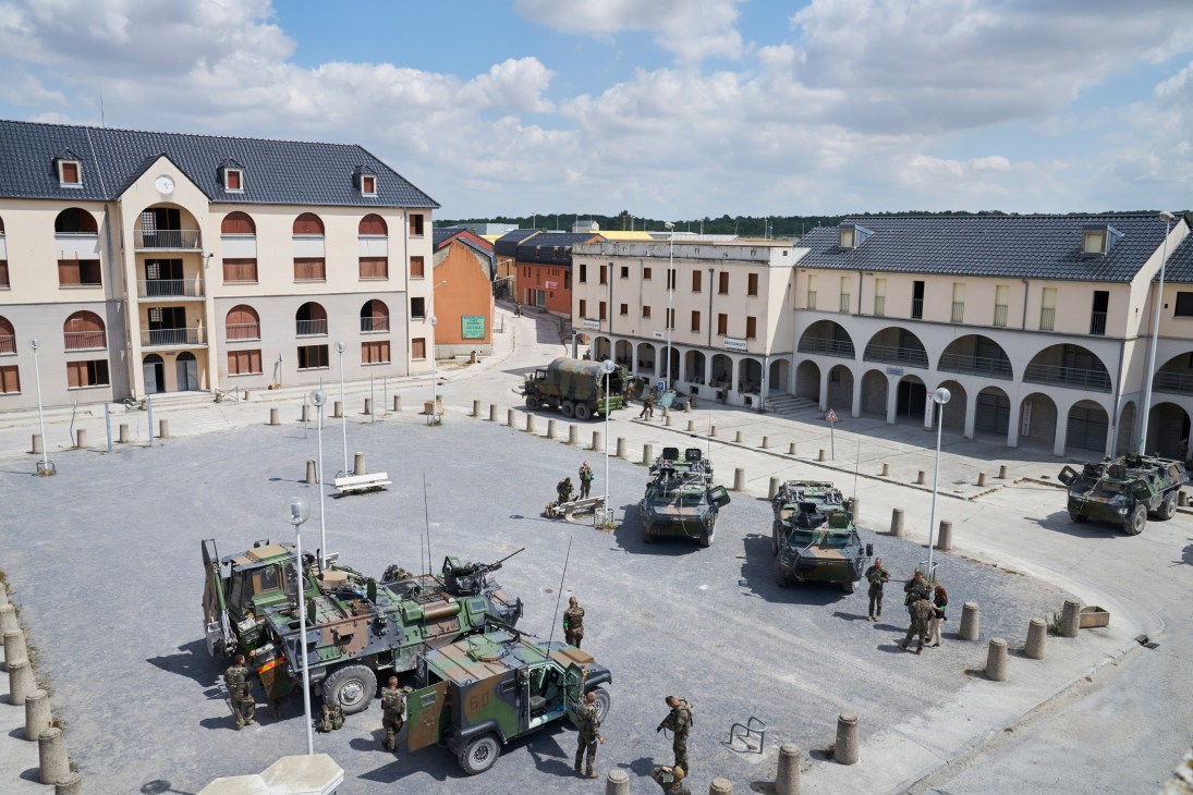 Military vehicles and soldiers conducting training exercises in a mock urban town square