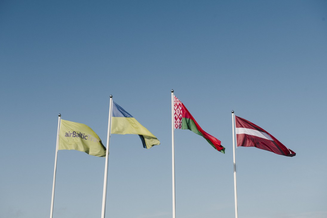 AirBaltic flag alongside flags of Latvia, Belarus, Ukraine and Latvia flying against blue sky