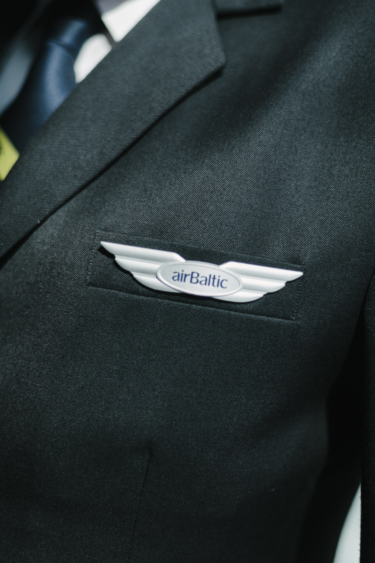 Close-up of AirBaltic pilot's wings badge on dark uniform jacket