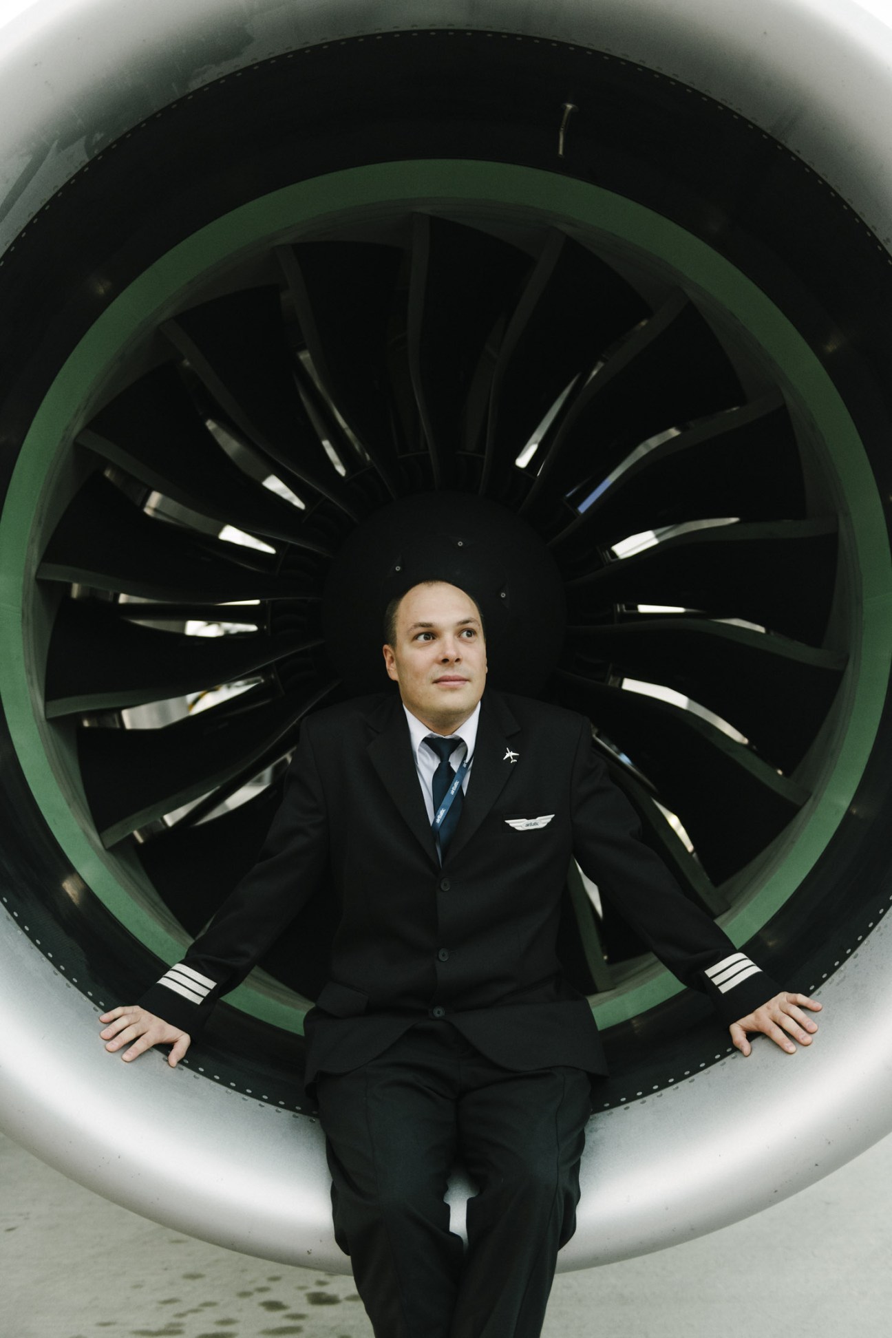 AirBaltic first officer Rivo Reidla in uniform posing within an aircraft engine with lime-green casing.