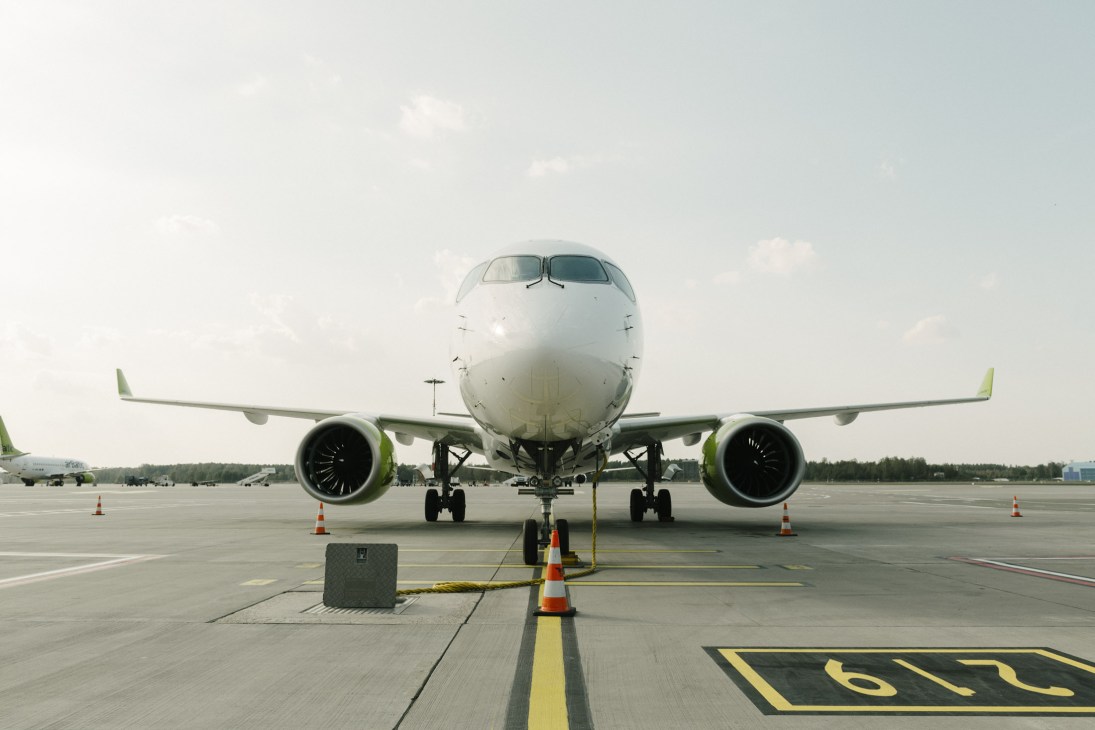 AirBaltic Airbus A220-300 aircraft on tarmac at Riga Airport with lime green engine accents