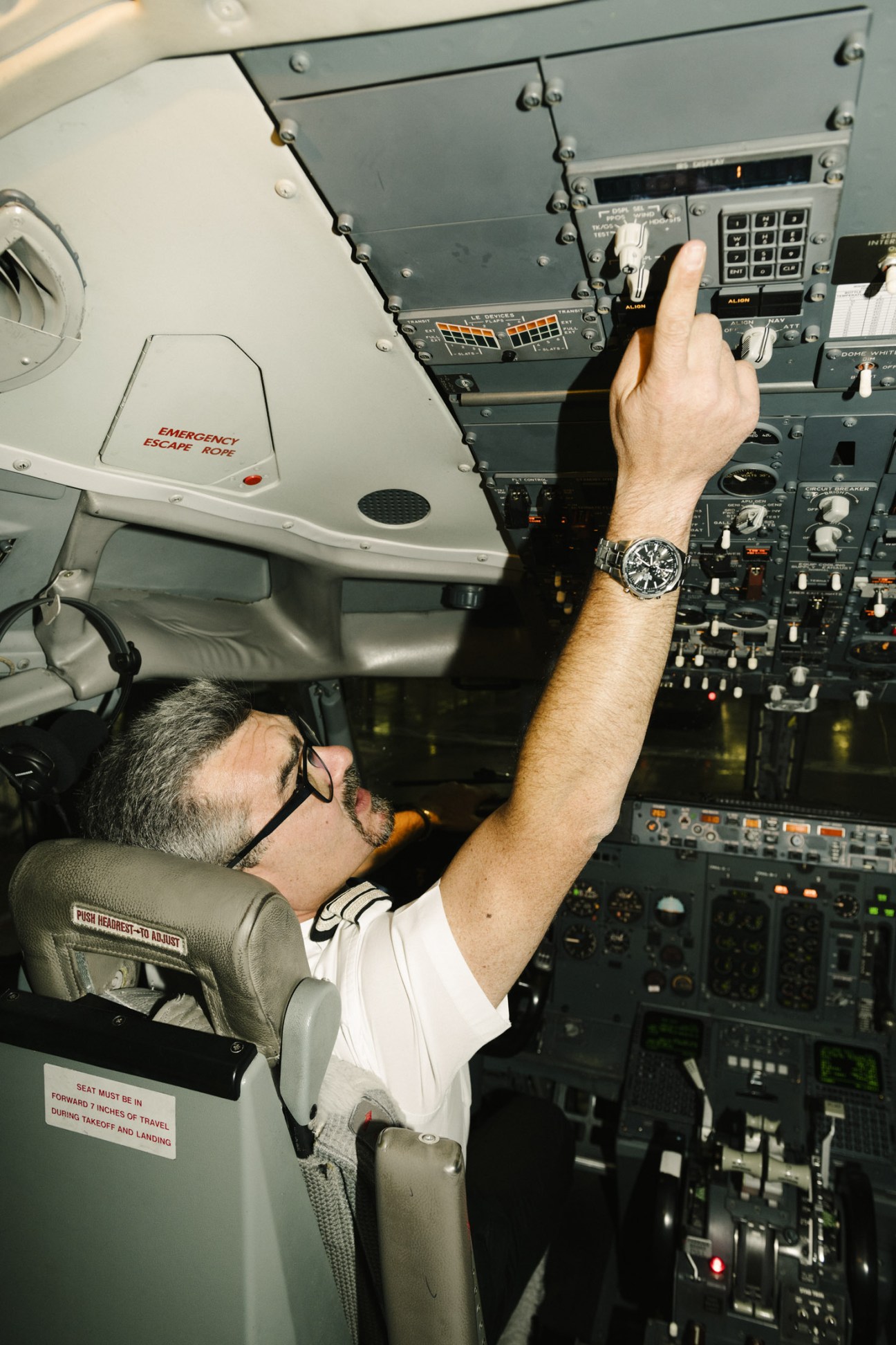 Aircraft engineer working on overhead panel controls inside an aircraft cockpit
