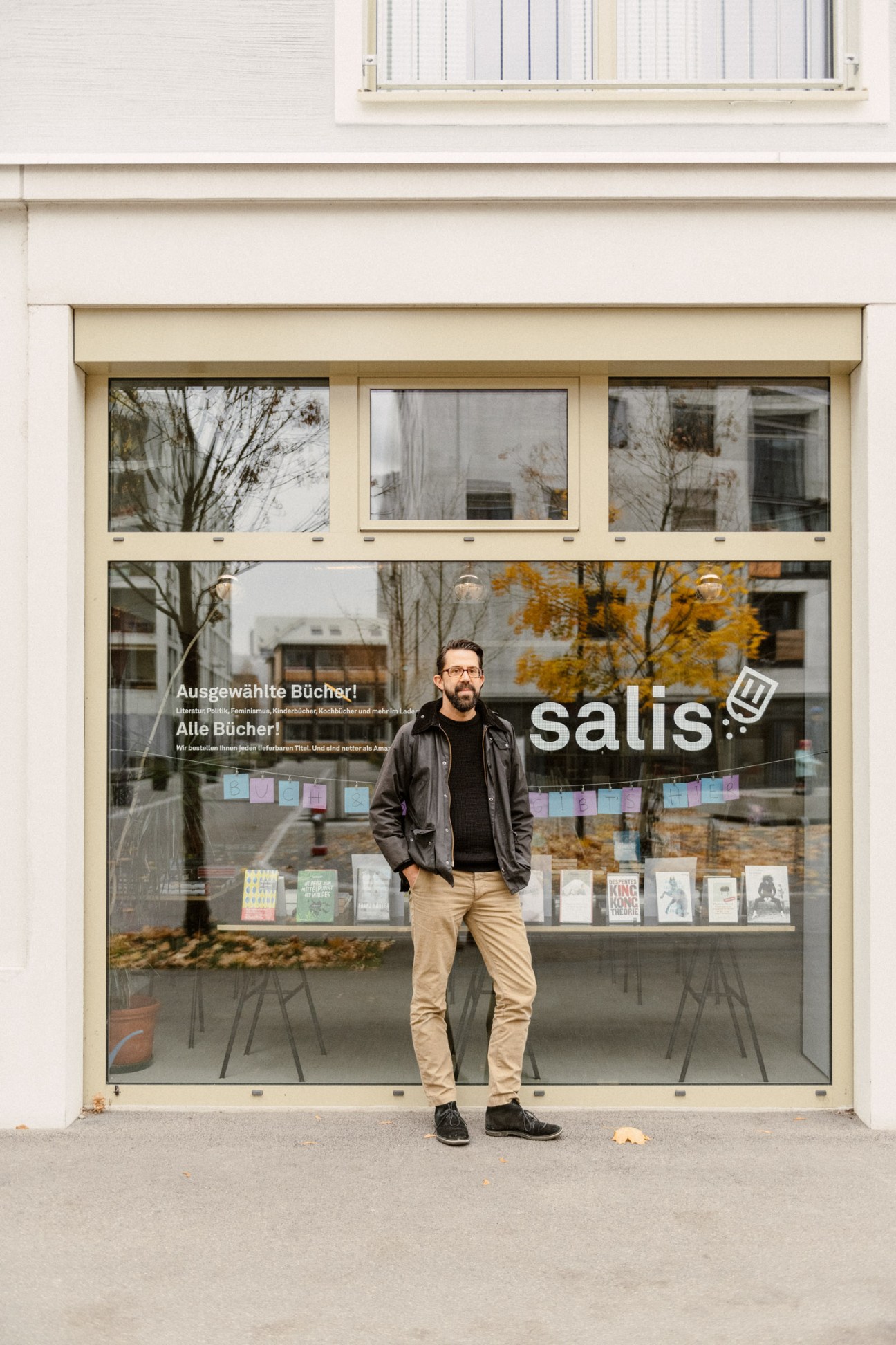 André Gstettenhofer stands in front of the Salis bookshop storefront with large windows displaying books.