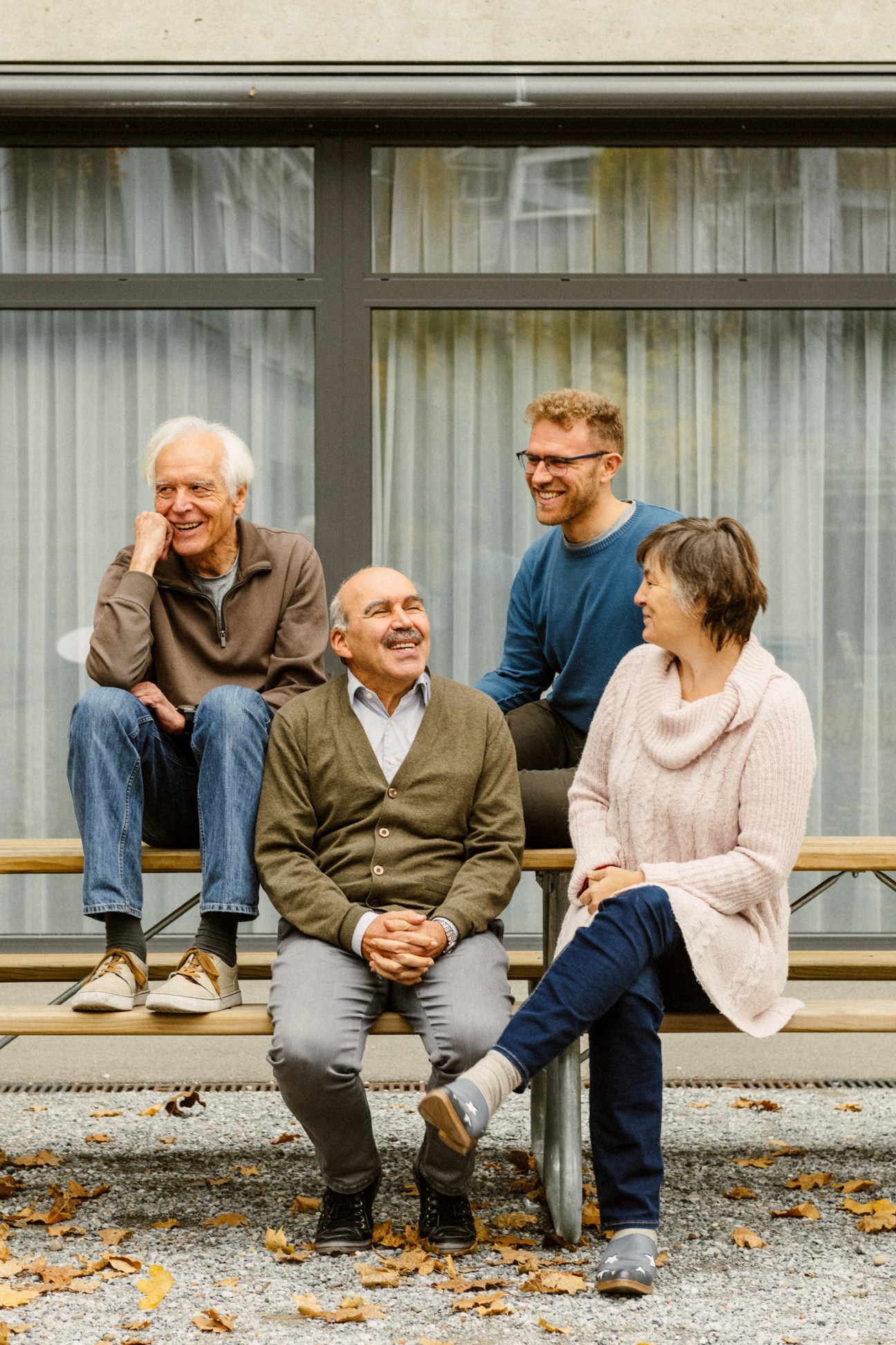Four residents sitting on a bench in front of a building, discussing the introduction of a local currency.