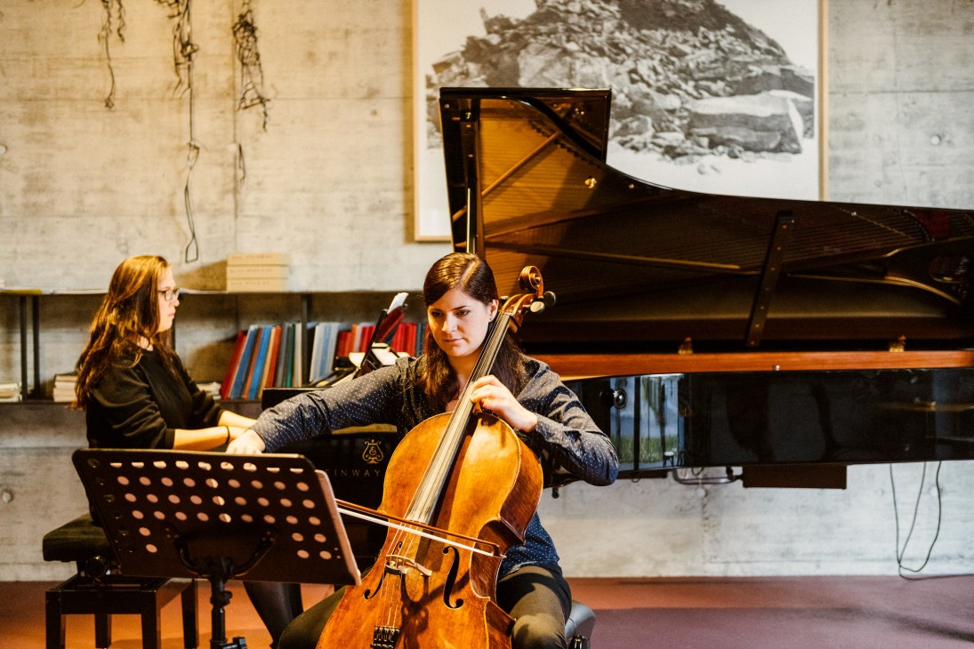 Cellist and pianist performing classical music in Hombi's Salon with a Steinway grand piano.