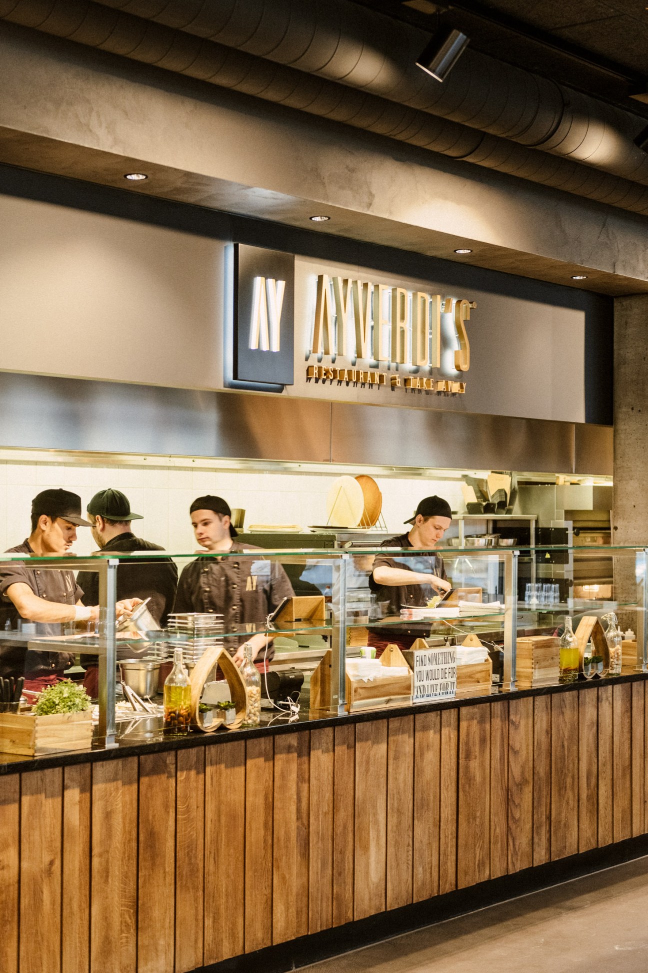 Staff working behind the counter at Ayverdi's kebab house with illuminated signage and open kitchen.