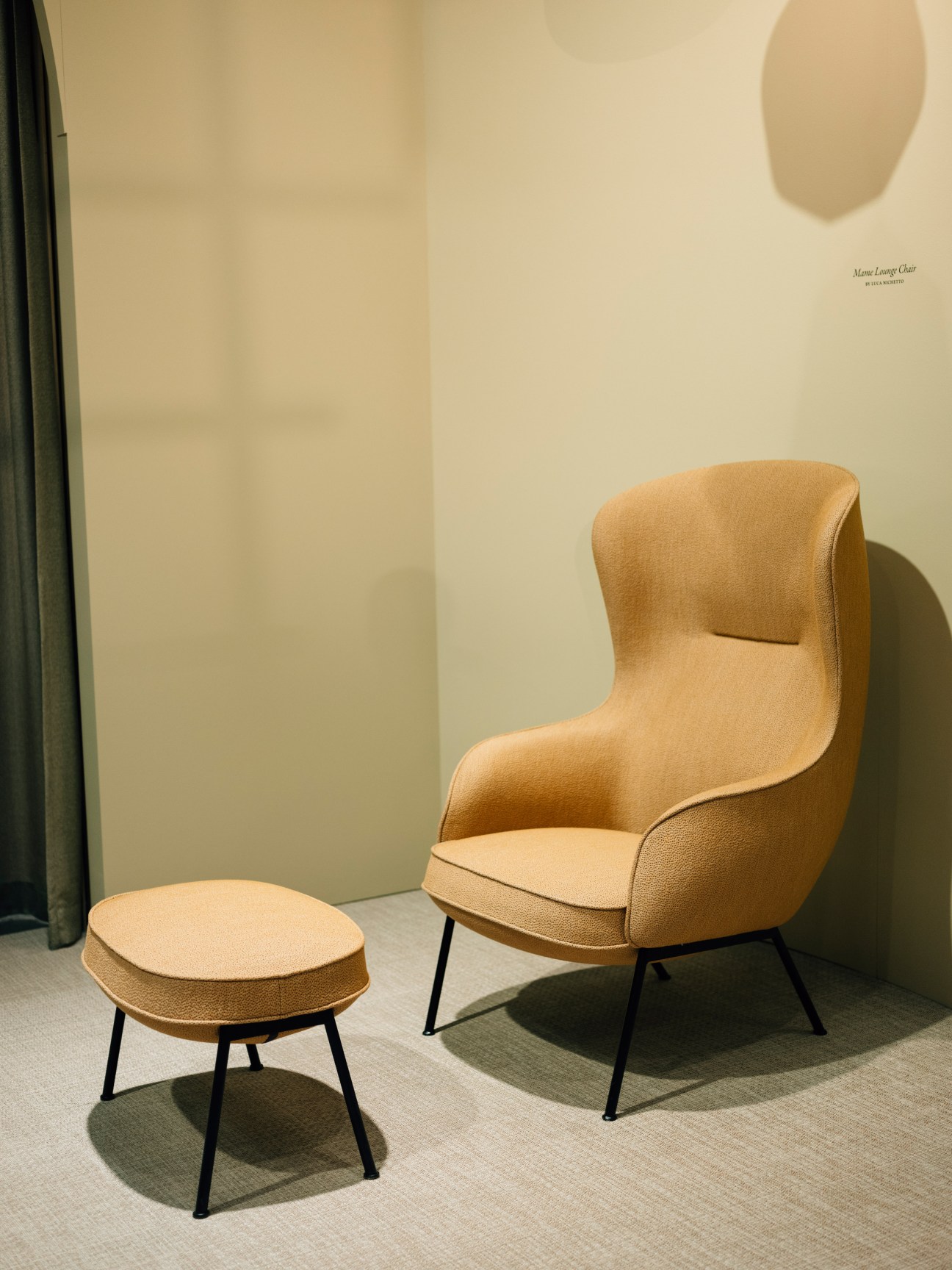 Tan upholstered lounge chair with black metal legs and matching ottoman on display at Stockholm Furniture & Light Fair.