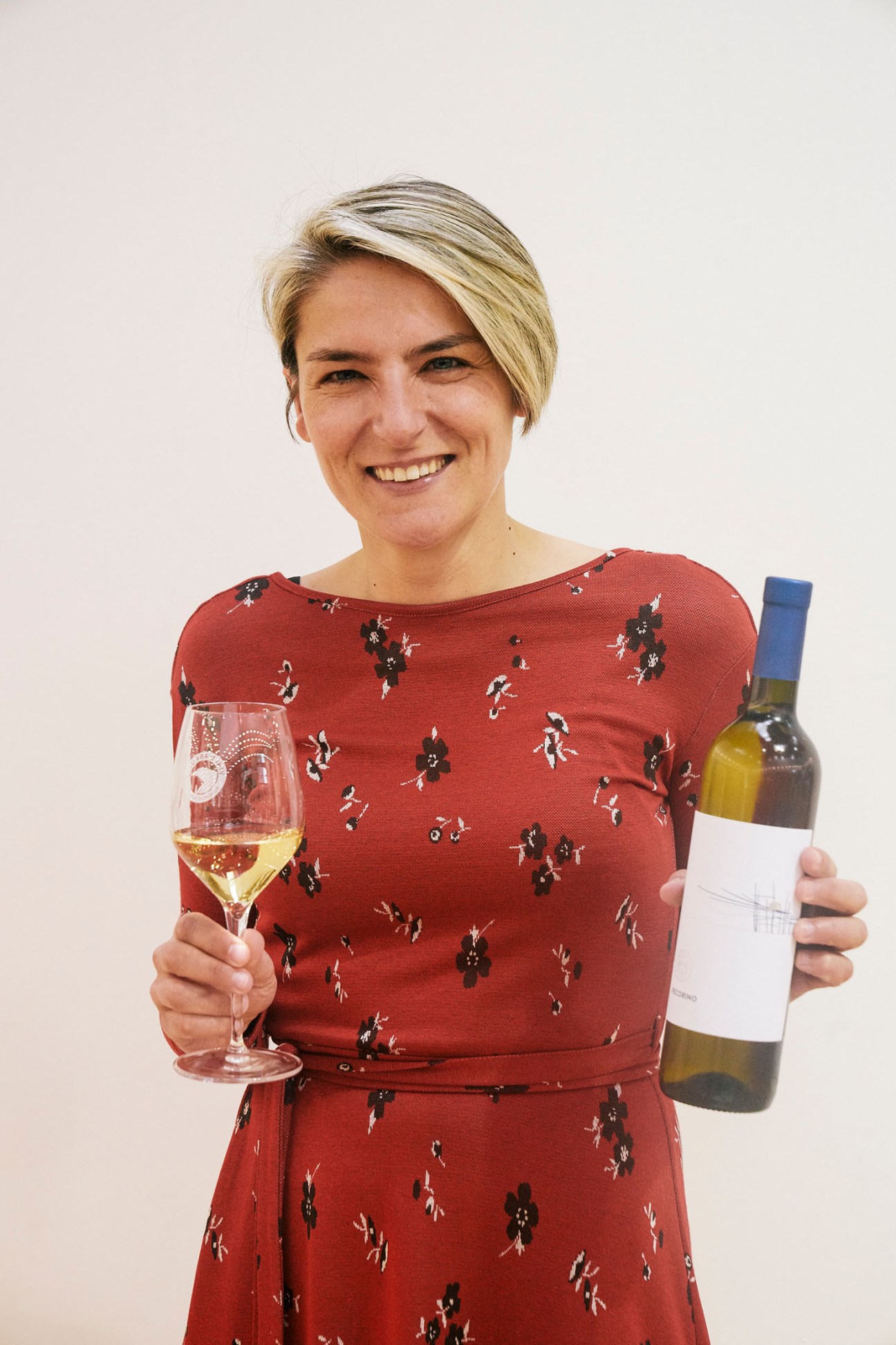 Valentina di Camillo, owner of Abruzzese winery Tenuta I Fauri, smiling while holding a wine glass and bottle.
