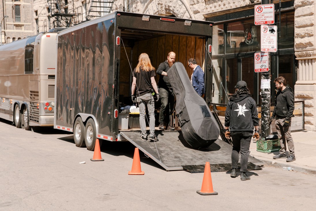Band members unload equipment from a trailer attached to Calexico's tour bus on a Chicago street.