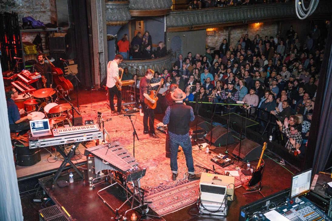 Calexico performs on stage at Thalia Hall in Chicago with band members playing instruments to a packed crowd.