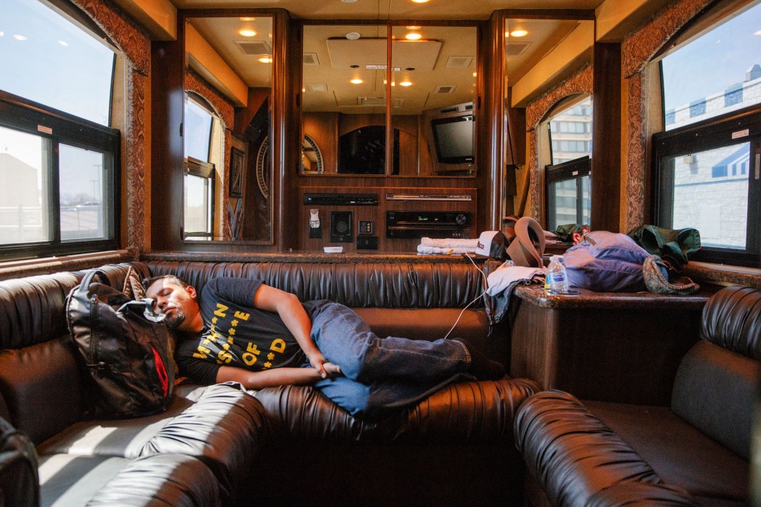 Jacob Valenzuela sleeping on a leather sofa inside Calexico's tour bus.