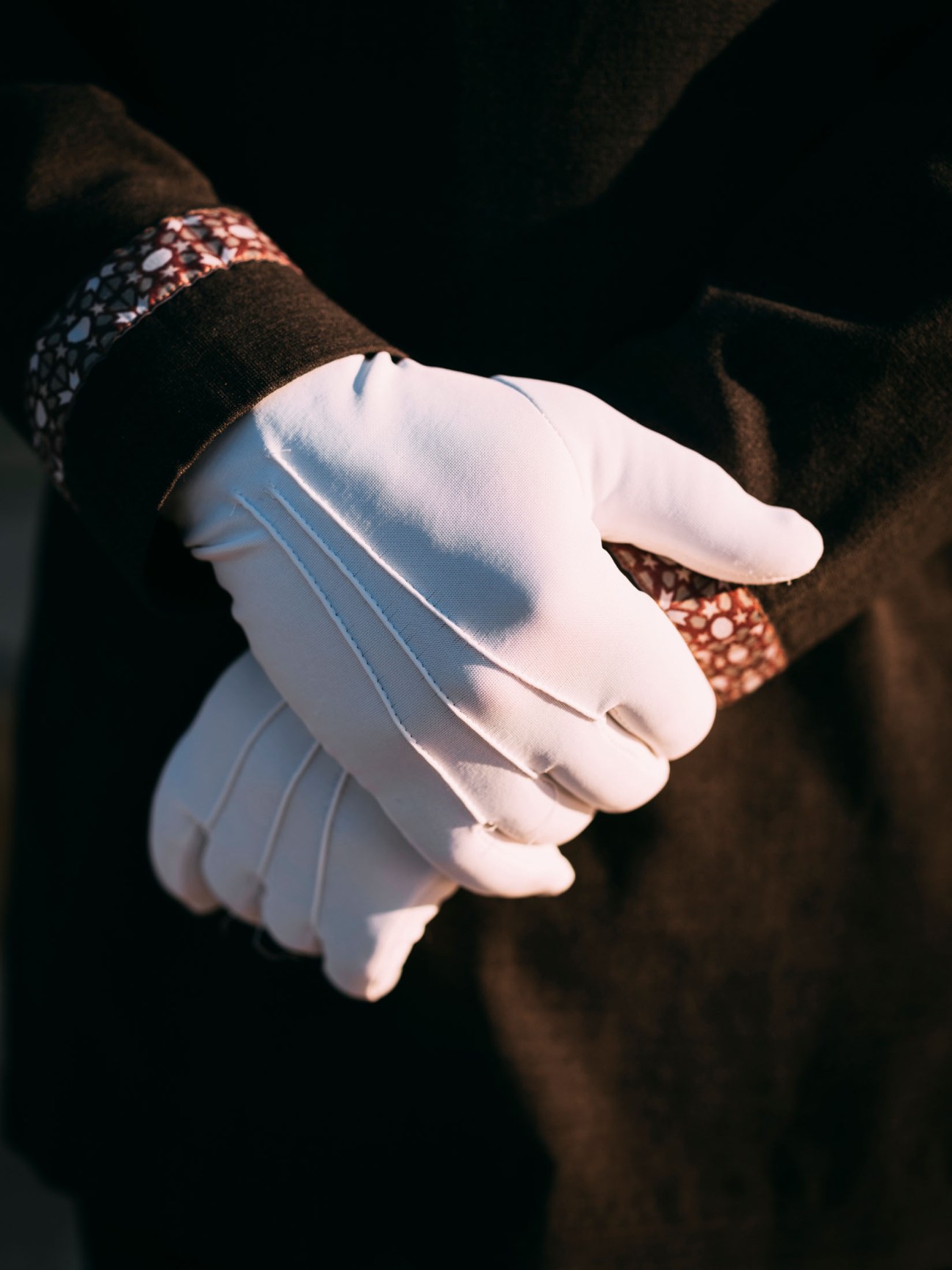 Close-up of a valet's white-gloved hand against dark background.