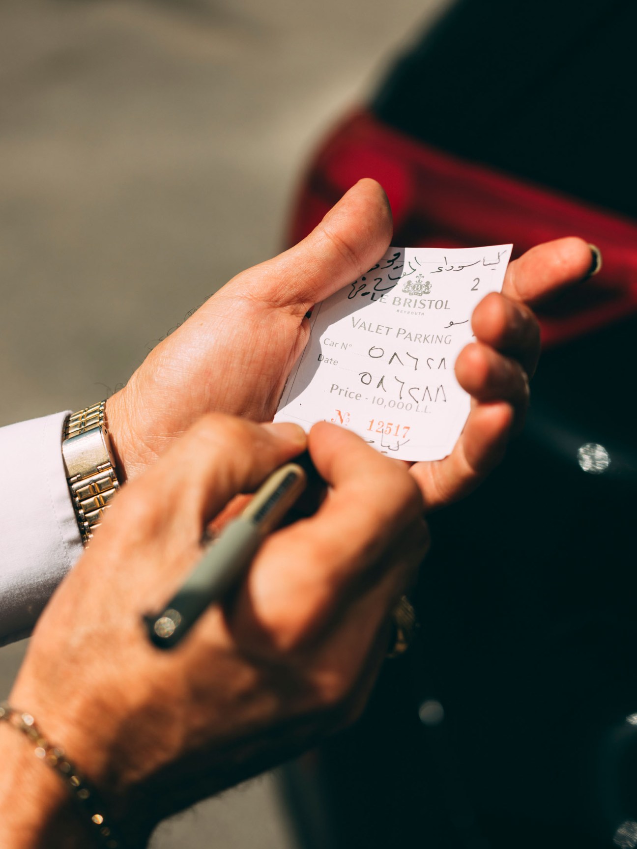 Hand holding a valet parking ticket from Bristol restaurant with car details and price written on it.
