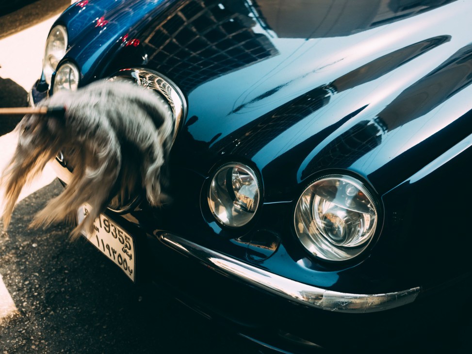 Close-up of a blue vintage car's front end with round headlights and chrome grille details.