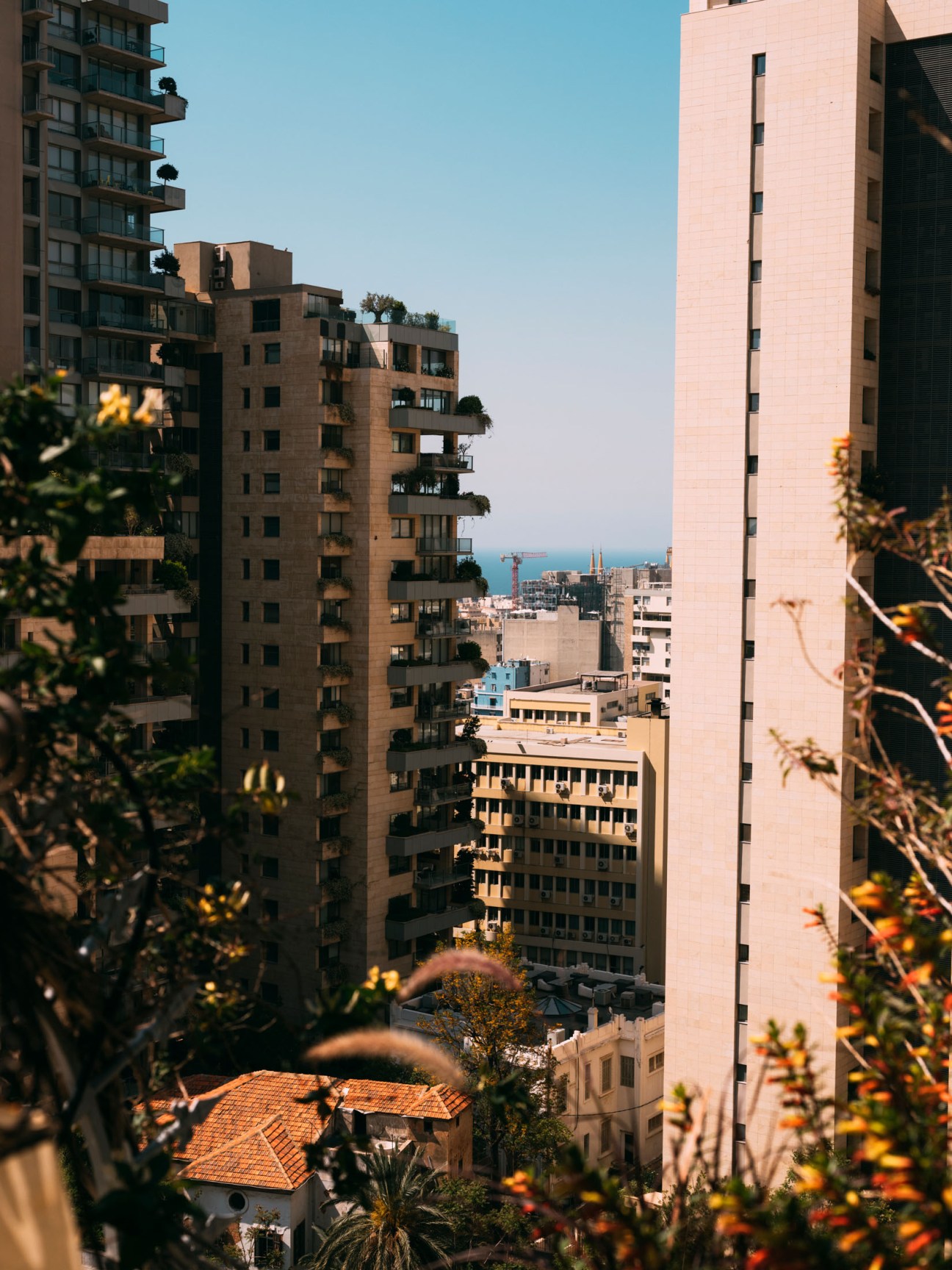 Aerial view of densely packed residential and commercial buildings in Beirut with sea visible in distance.