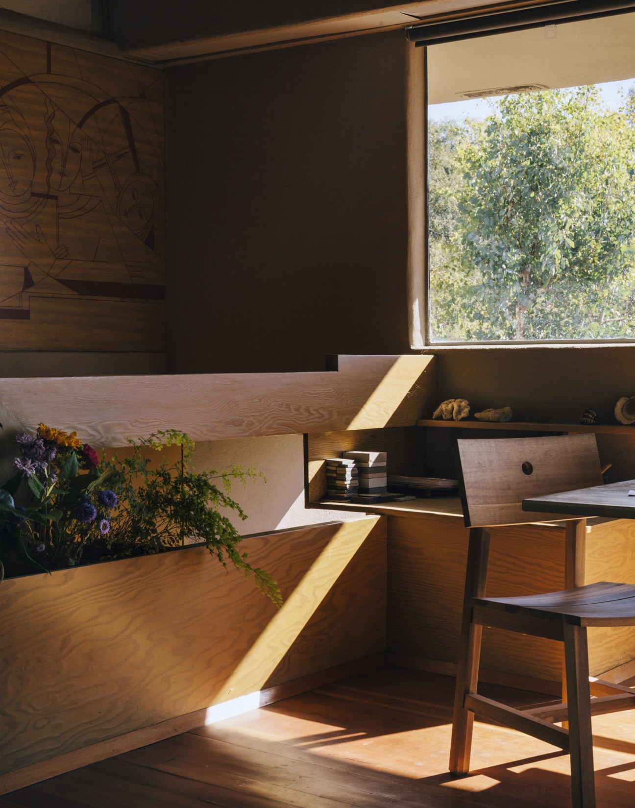 Art by Osheroff's mother sits above the stairs in the modernist Oliver House interior with wooden shelving and natural light.