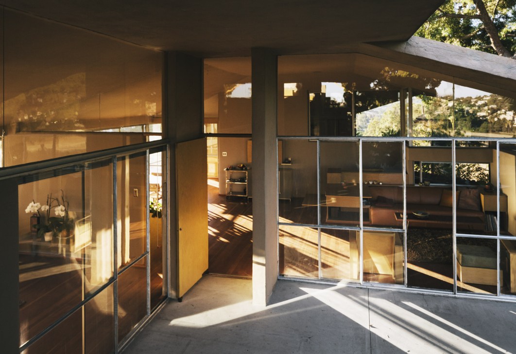 Interior view of the Oliver House showing extensive glass partitions and a floating wing-like roof with natural light streaming in.