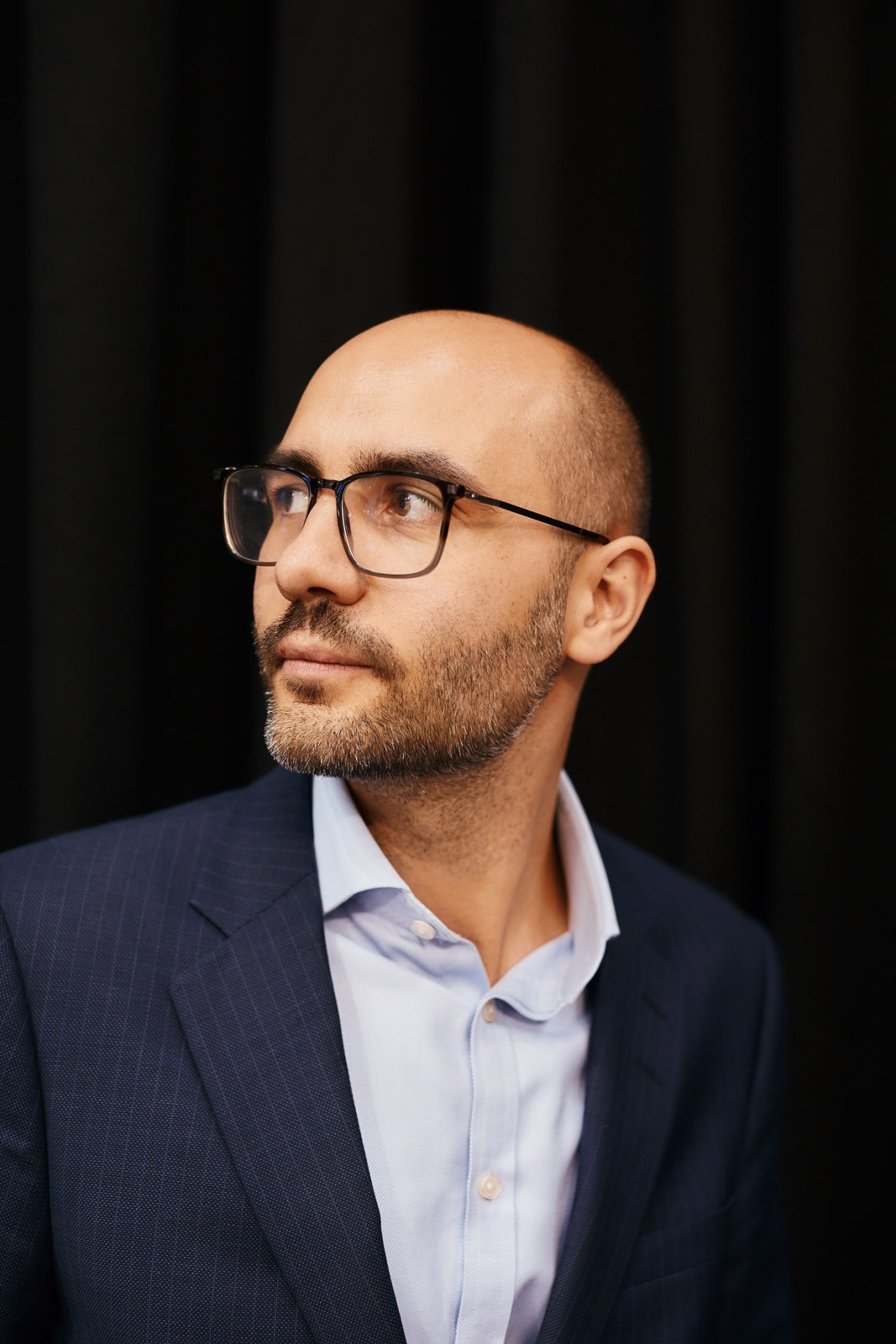 Chris-Norman Sauer, head of acquisitions at Premier Inn, wearing glasses and business attire against a dark background.