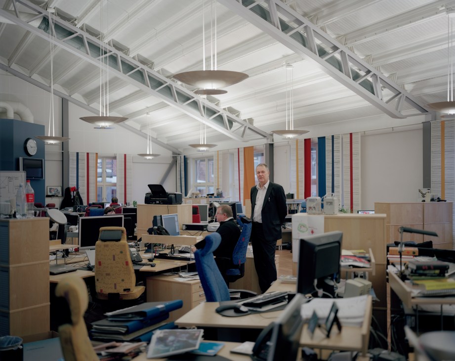 Interior of a modern office space with wooden desks, colorful partitions, and workers at computers.