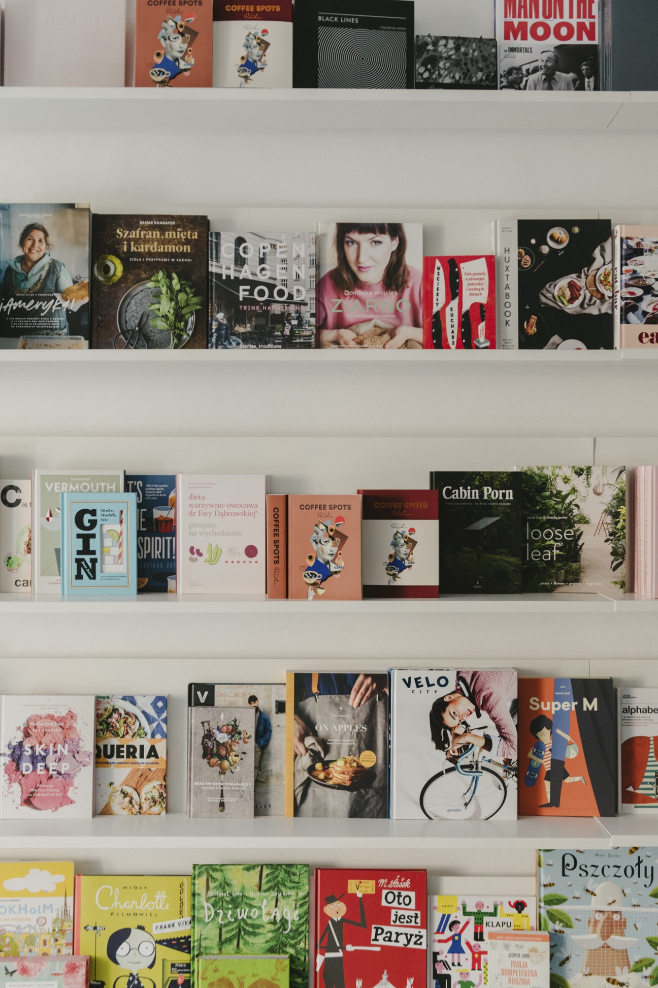 White shelving unit displaying a curated collection of graphic design books and publications with colorful covers.