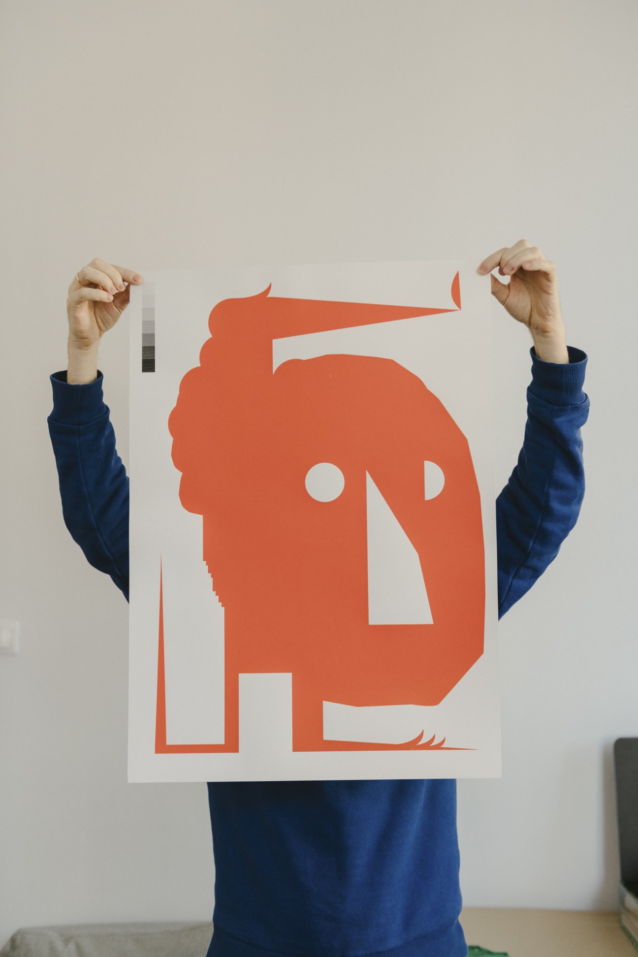Filip Tofil holds up a graphic design poster featuring a bold red silhouette and geometric shapes.