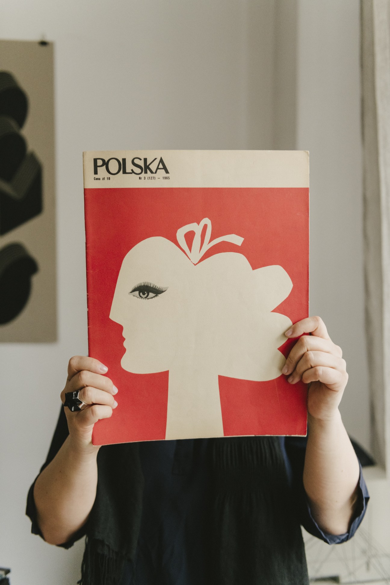 Person holding a Polska magazine cover from 1985 featuring a minimalist white female profile illustration on red background