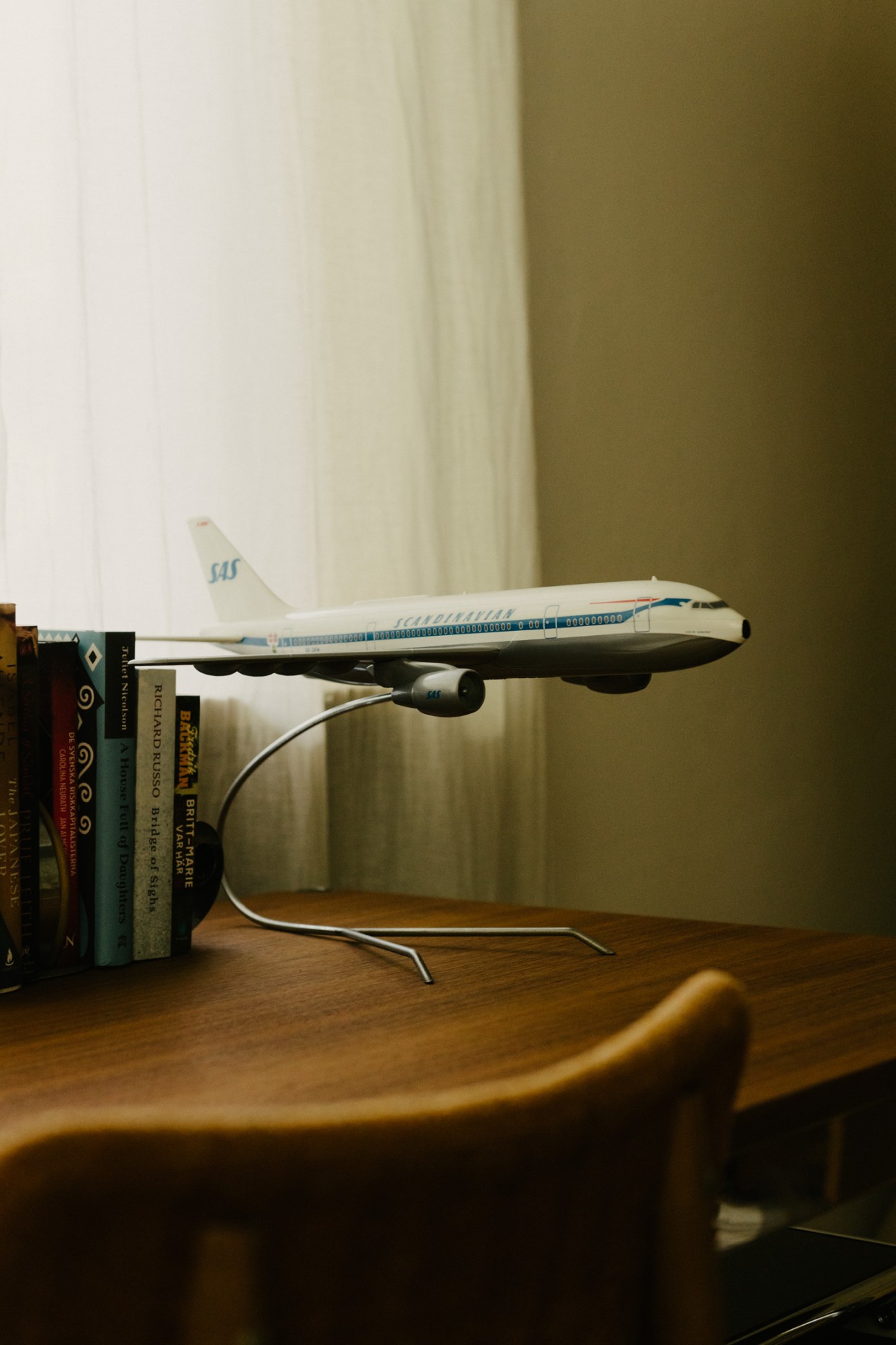 Scandinavian Airlines model aeroplane displayed on wooden surface next to stacked books.