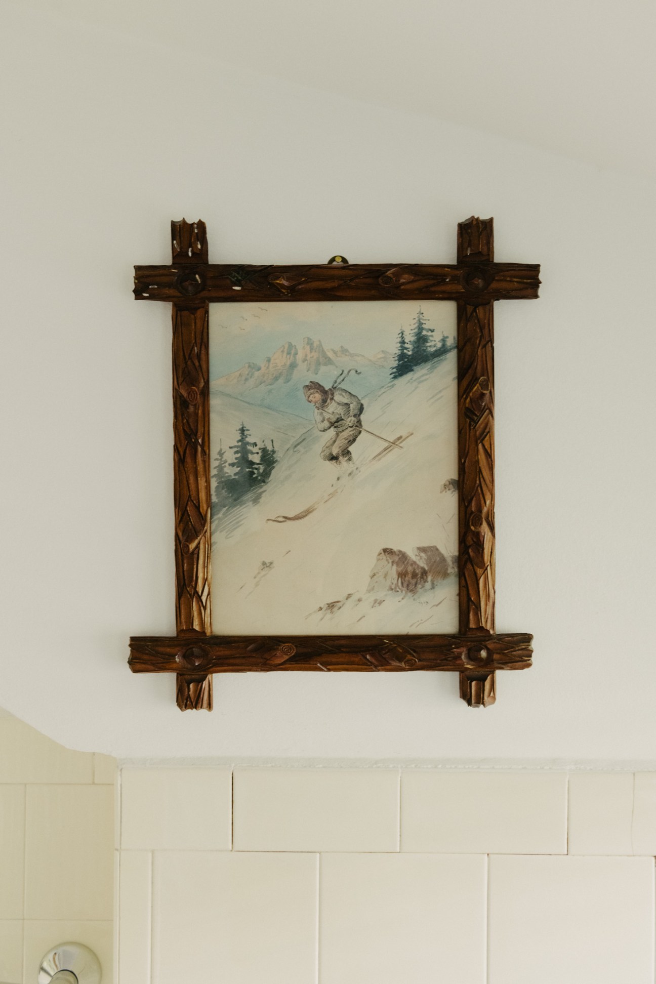 Vintage wooden framed ski descent artwork depicting a skier on snowy alpine slopes with evergreen trees and mountain peaks in background.
