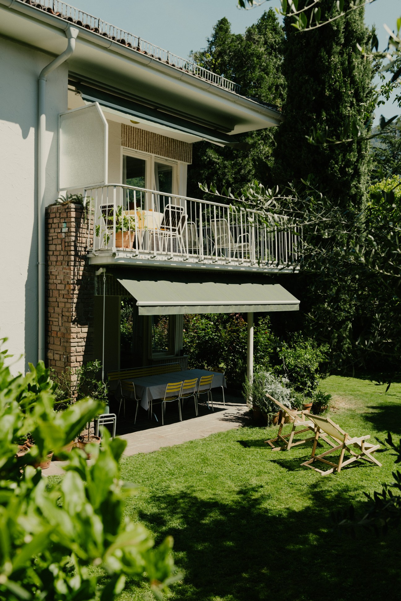 Italian-made loungers on a sunny lawn overlooking ivy-covered walls and a terraced garden.