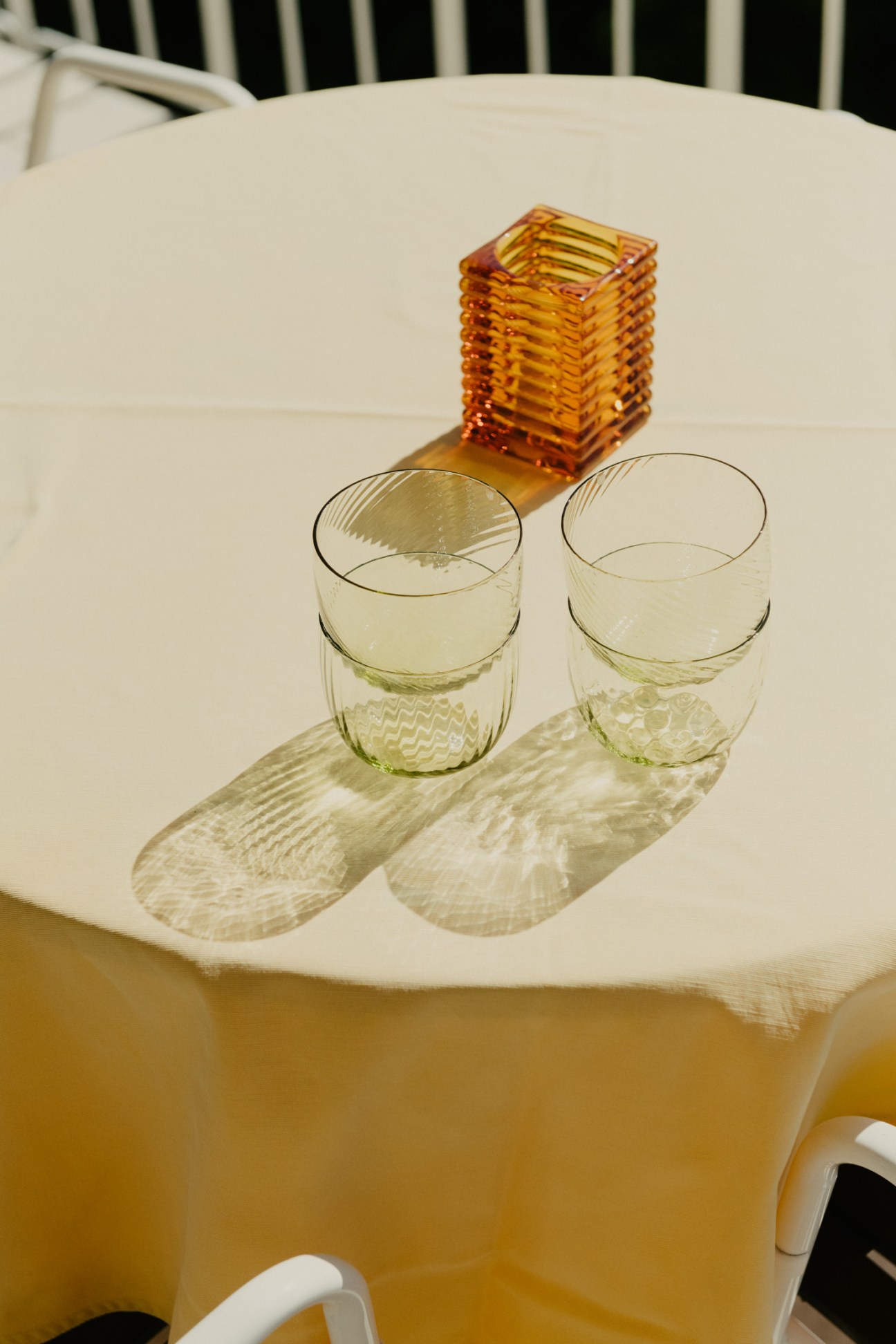 Two Italian glasses from Stillsegler and an amber glass vase on a white table.