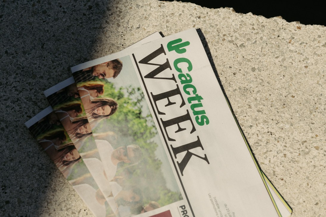 Cactus supermarket newspaper lying on concrete ground with product photography visible.