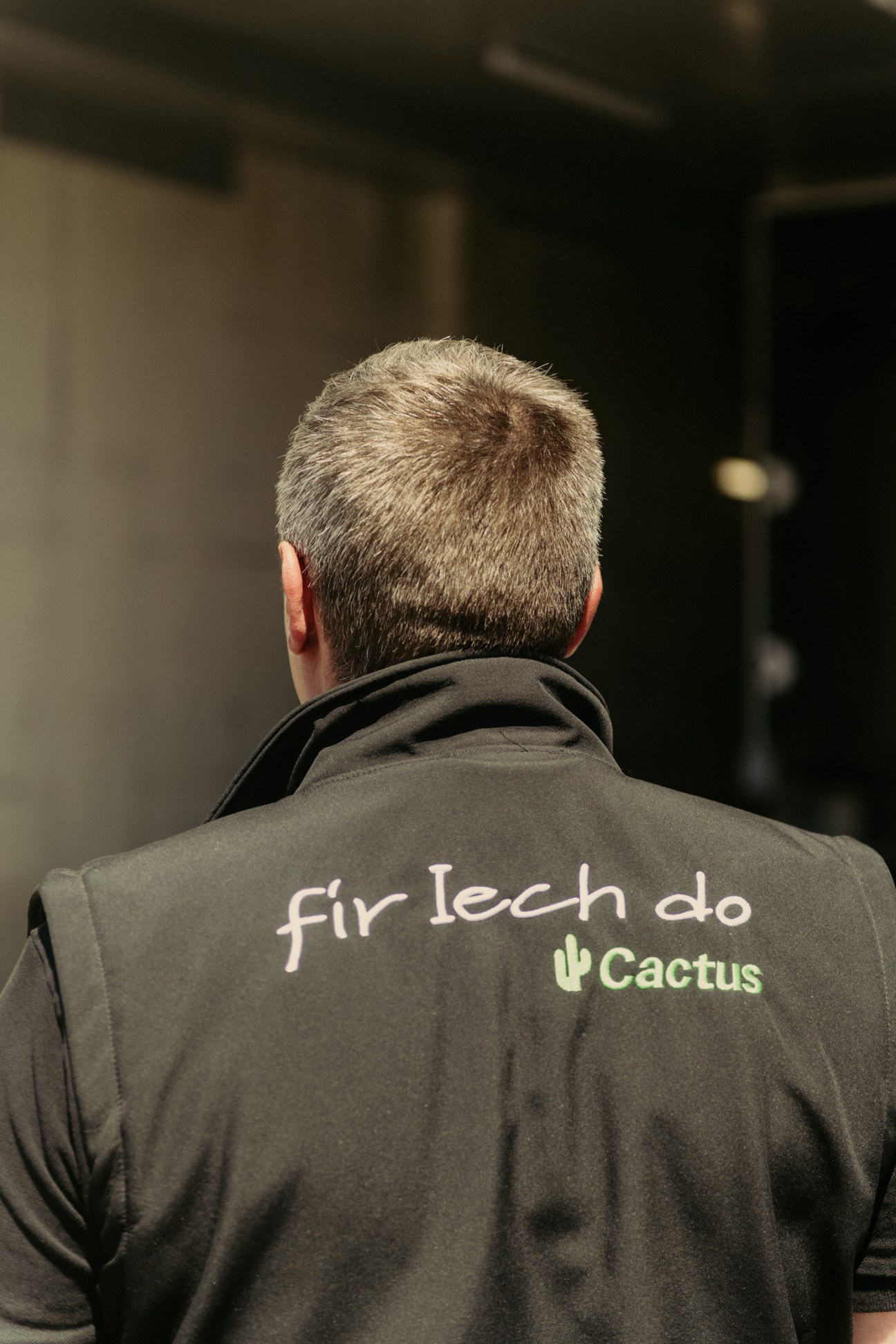 Person wearing black Cactus staff vest with 'Fir Iech do' slogan and cactus logo on back.