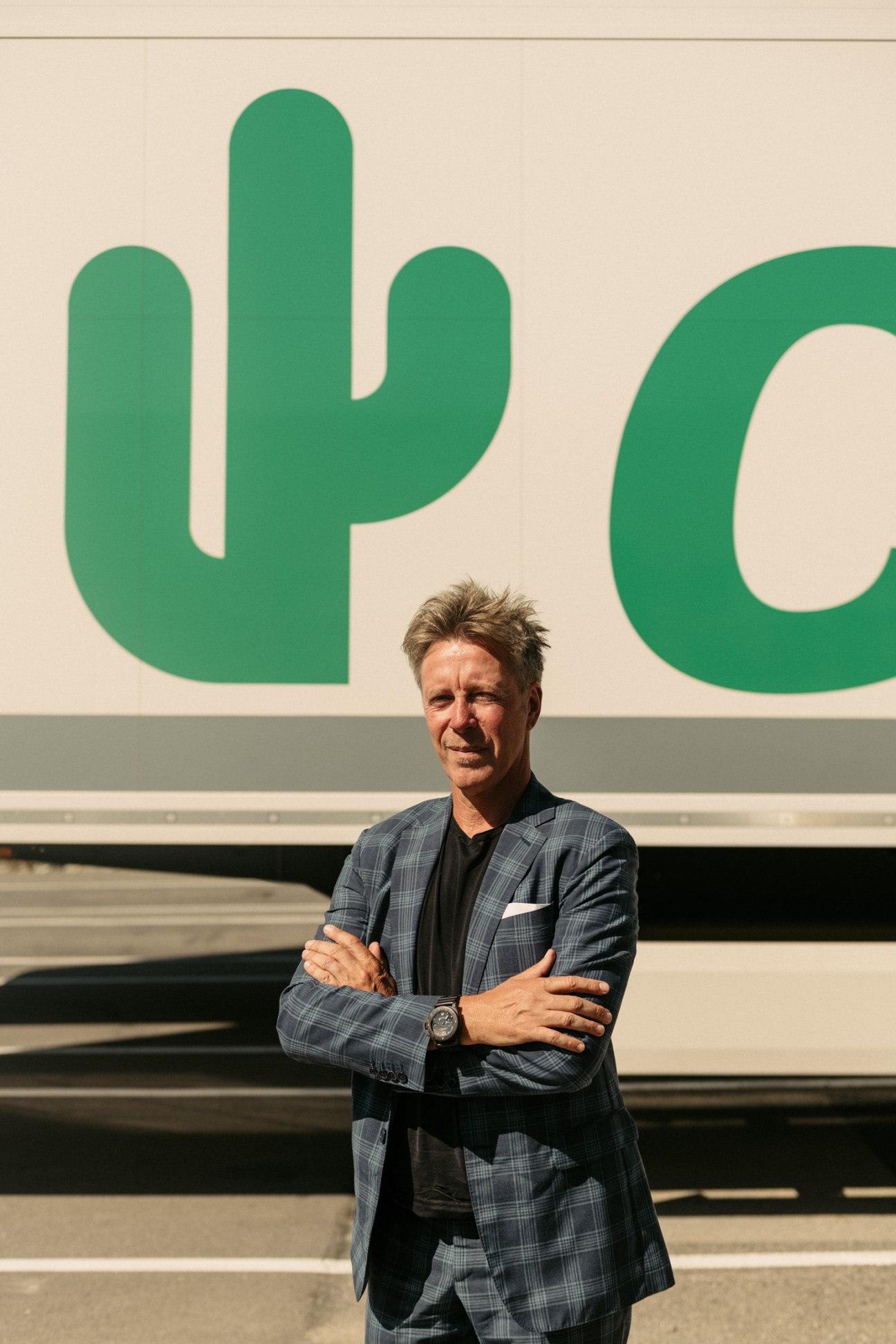 Laurent Schonckert, managing director of Cactus supermarket, stands with crossed arms in front of the green cactus logo.