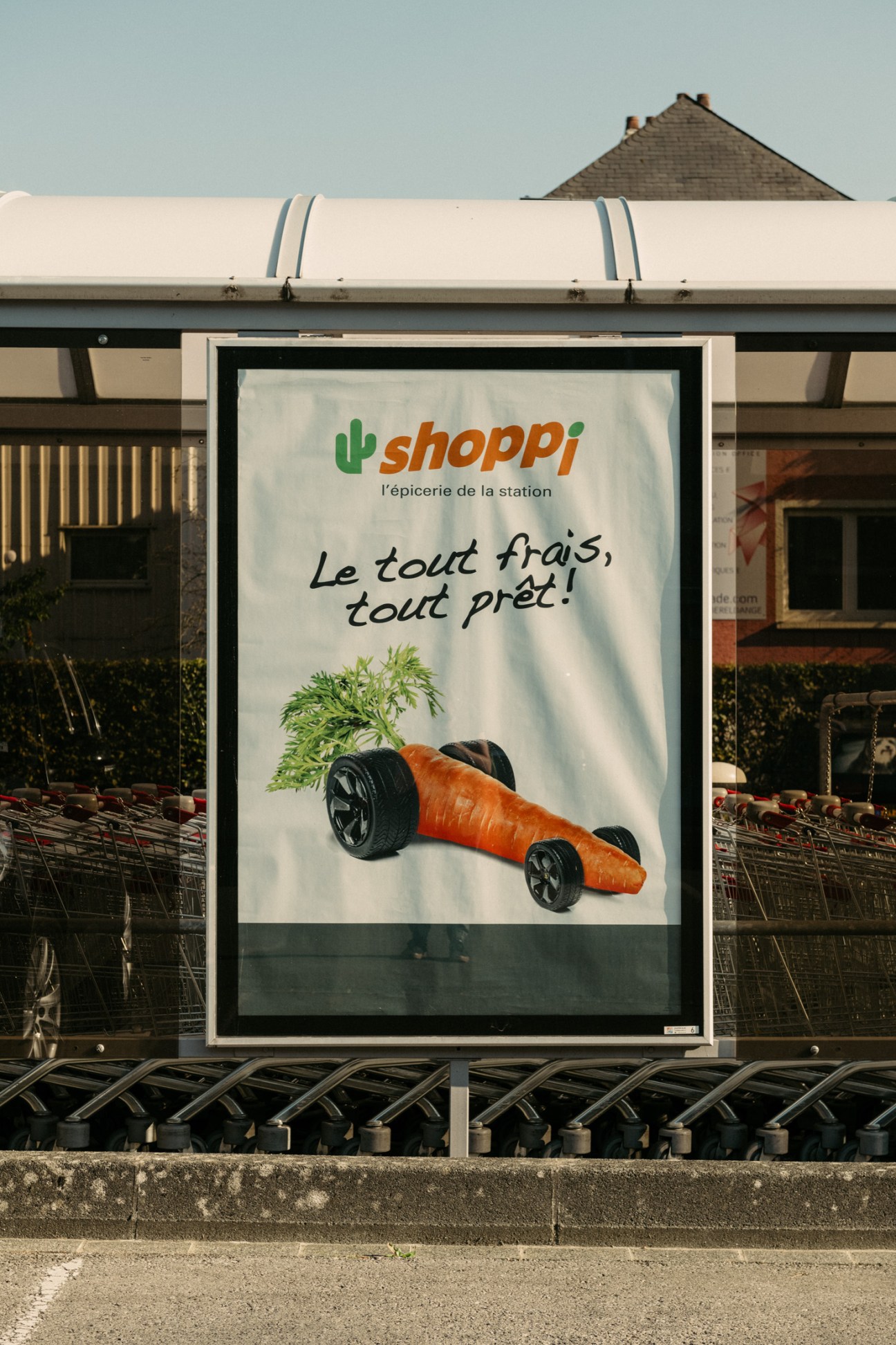 Shoppi store advertisement billboard with carrot-shaped race car and French tagline.