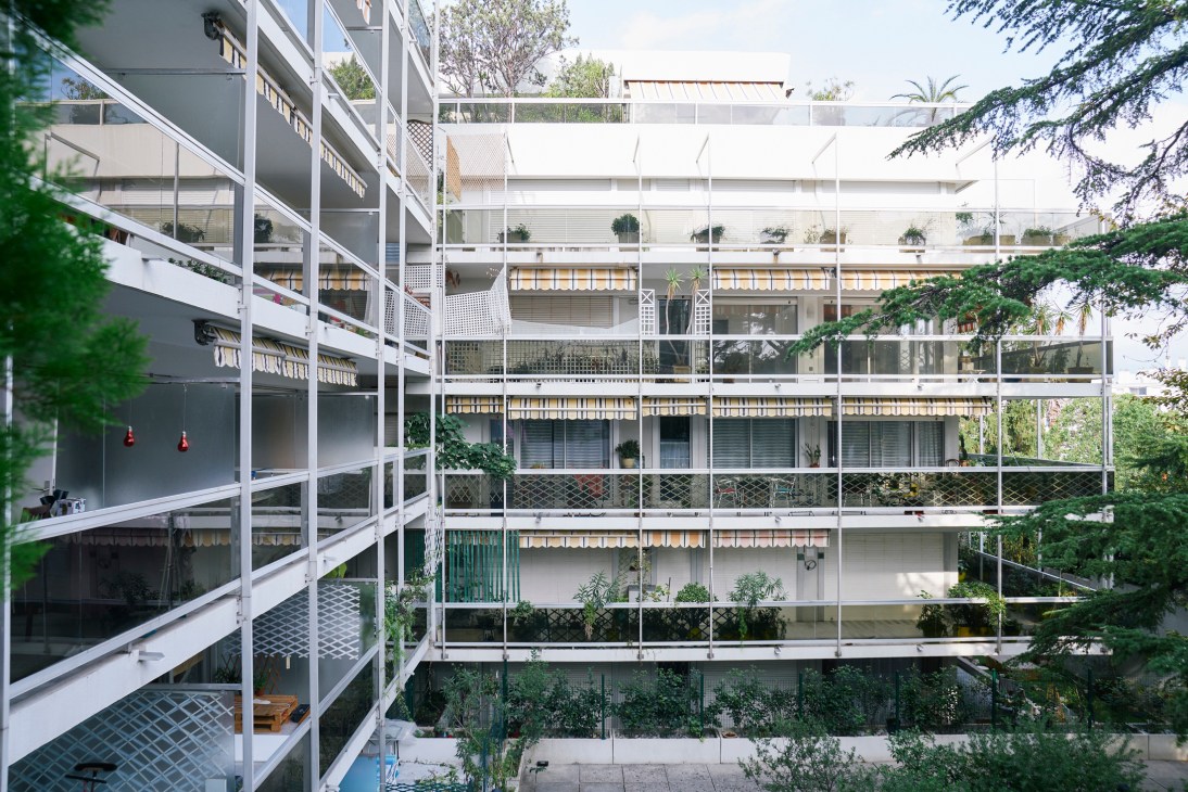 Apartment balconies with orange awnings surrounded by Mediterranean landscaping and palm trees