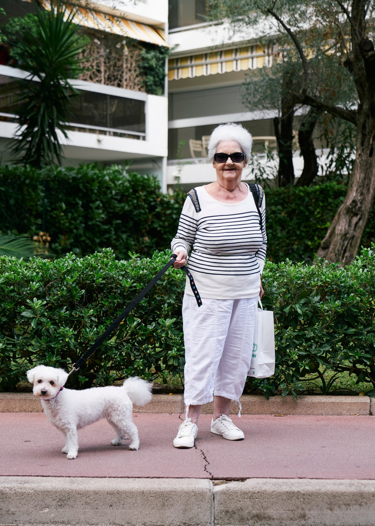 Female resident walking small dog through landscaped grounds of Mas de Tanit