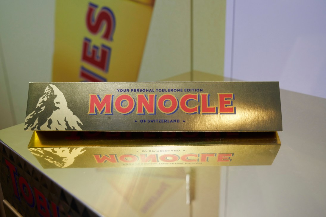 Gold Toblerone chocolate bar box with mountain logo and red lettering on reflective surface