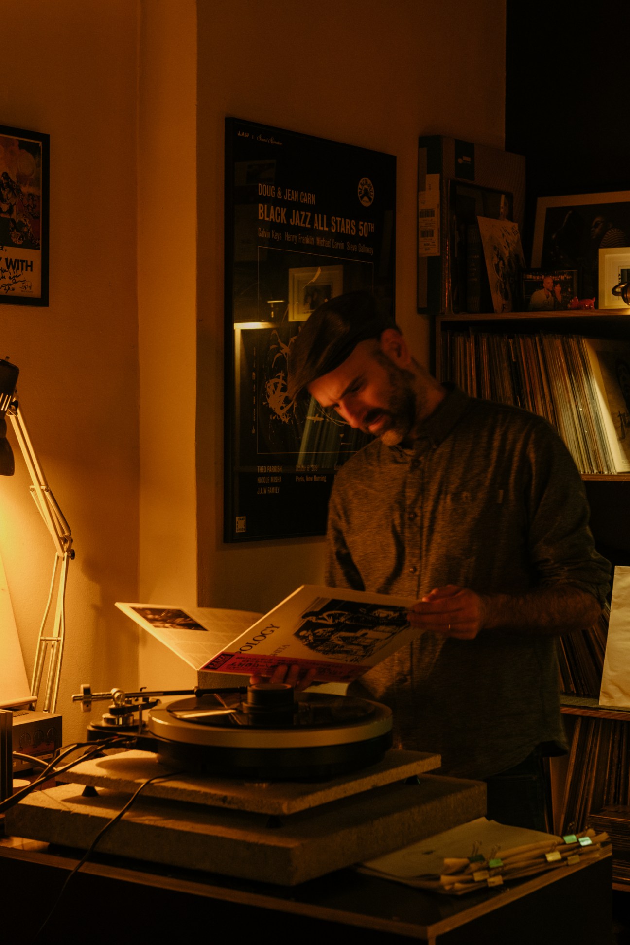 DJ selecting vinyl records at Rhinoçéros listening bar in Berlin with warm lighting and jazz posters on walls.