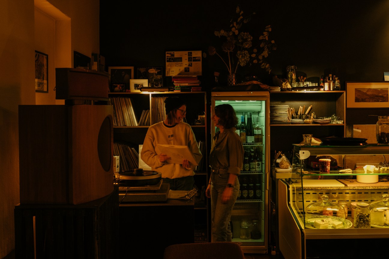 Interior of Rhinoçéros bar in Berlin with warm lighting, vinyl records on shelves, and a refrigerated display case.