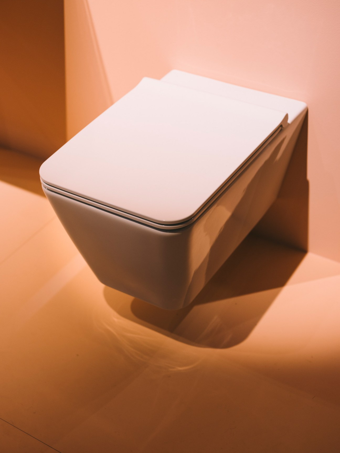 Laufen's Cleanet Navia shower toilet with minimalist white seat on warm-toned backdrop.