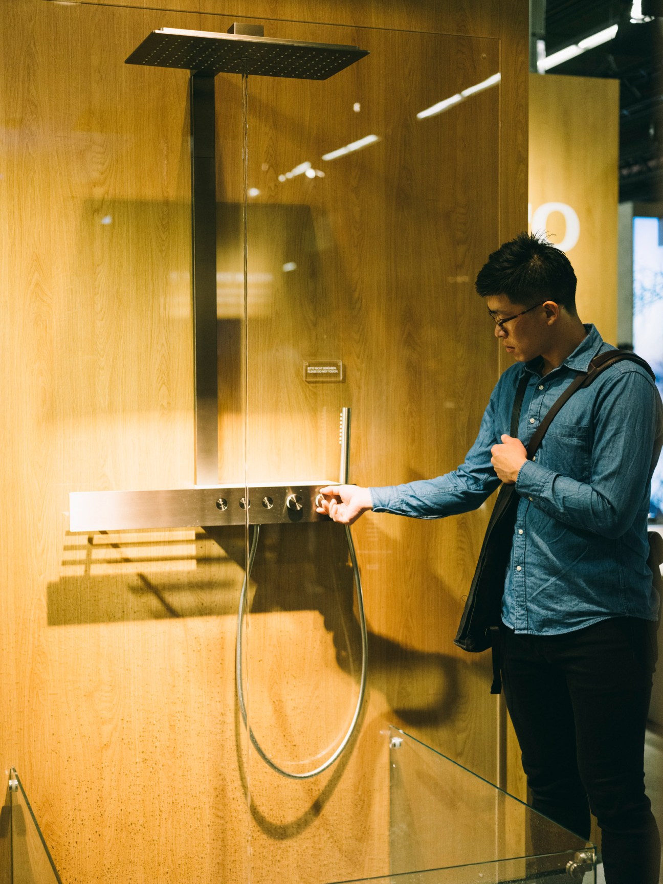 Man testing Toto's new shower design with overhead rainfall showerhead and wall-mounted controls.