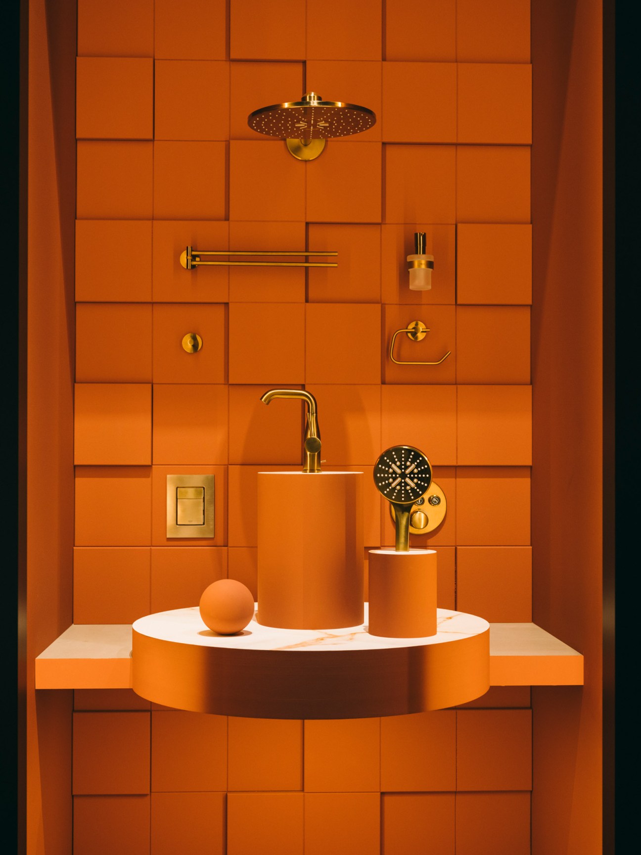 Orange bathroom installation featuring brass fixtures and showerhead against tiled wall.