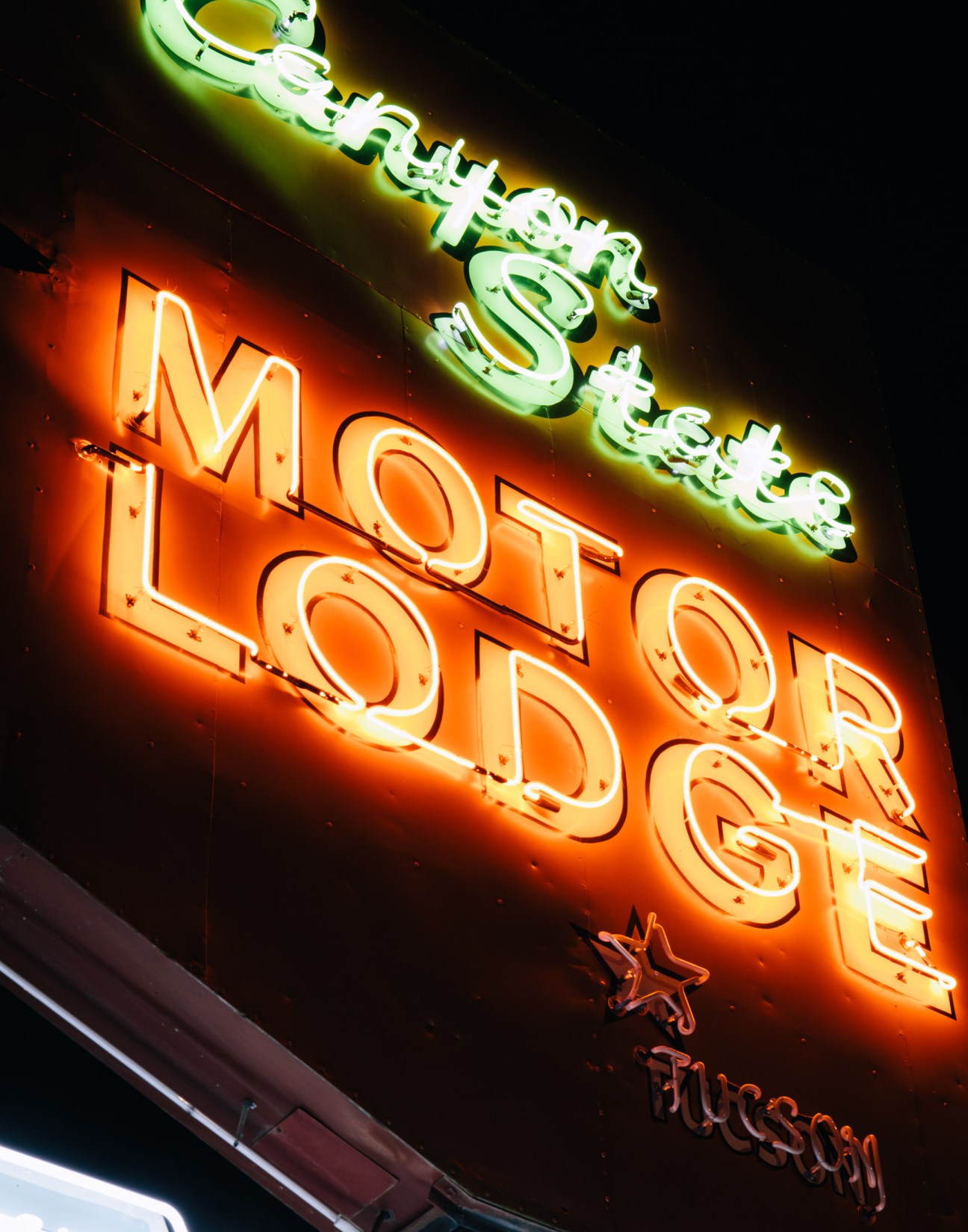 Illuminated neon signs at dusk on Tucson's Miracle Mile, including the Monterey Court and Ghost Ranch Lodge.