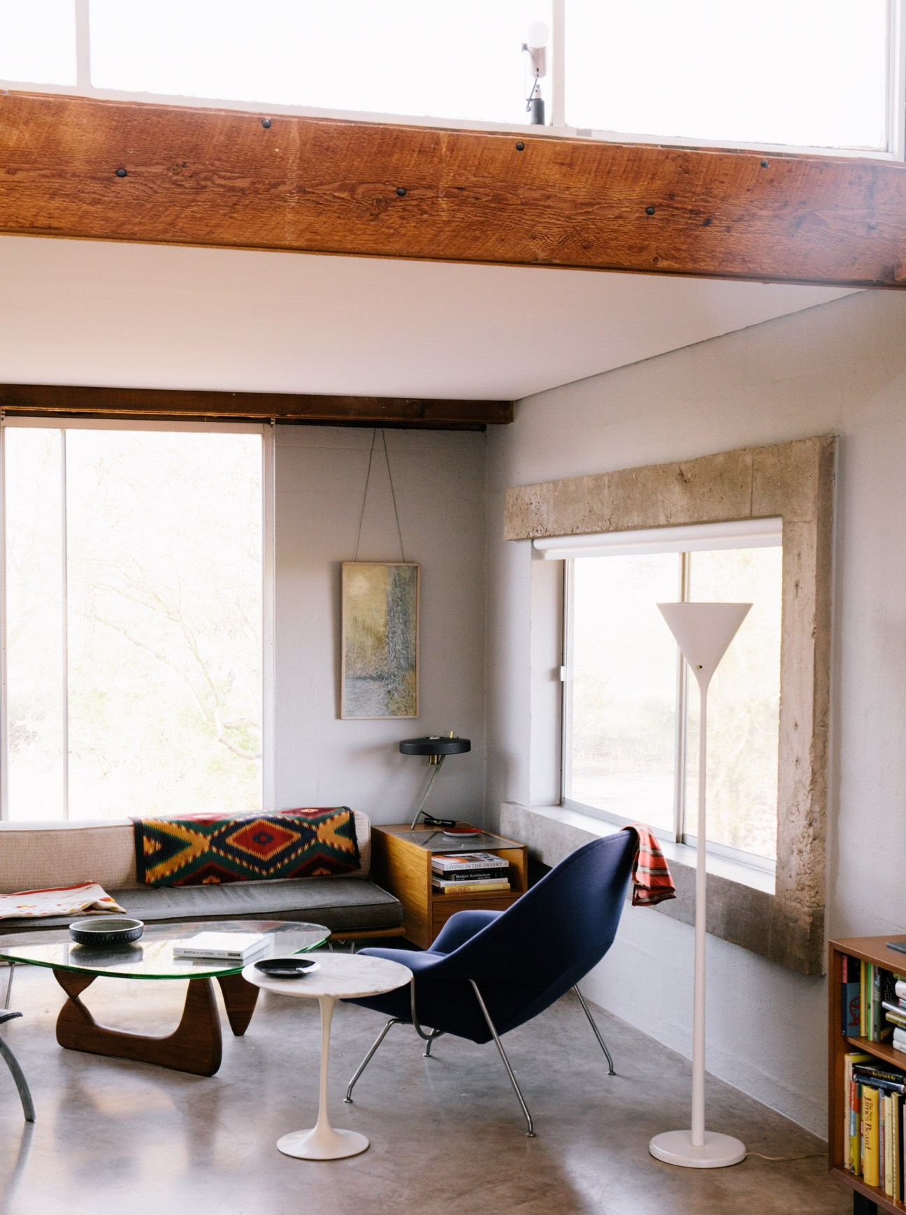 Desert modernist living room with wooden beam ceiling, mid-century furniture, and large windows.