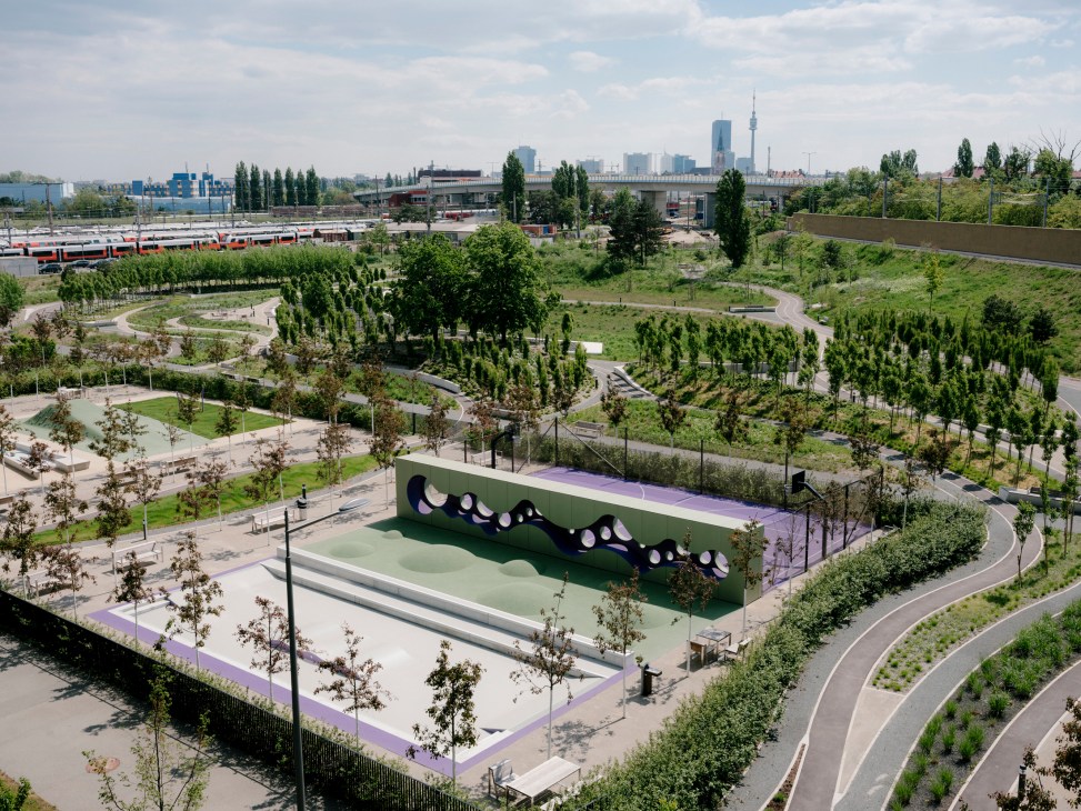 Aerial view of Klinik Floridsdorf hospital grounds with landscaped therapy gardens, trees, and curved pathways surrounding a distinctive green building with purple accents.