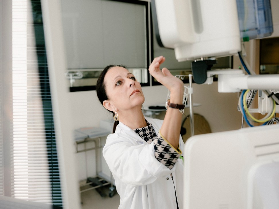 Medical director Margot Löbl looking upward in a modern hospital facility with medical equipment visible.