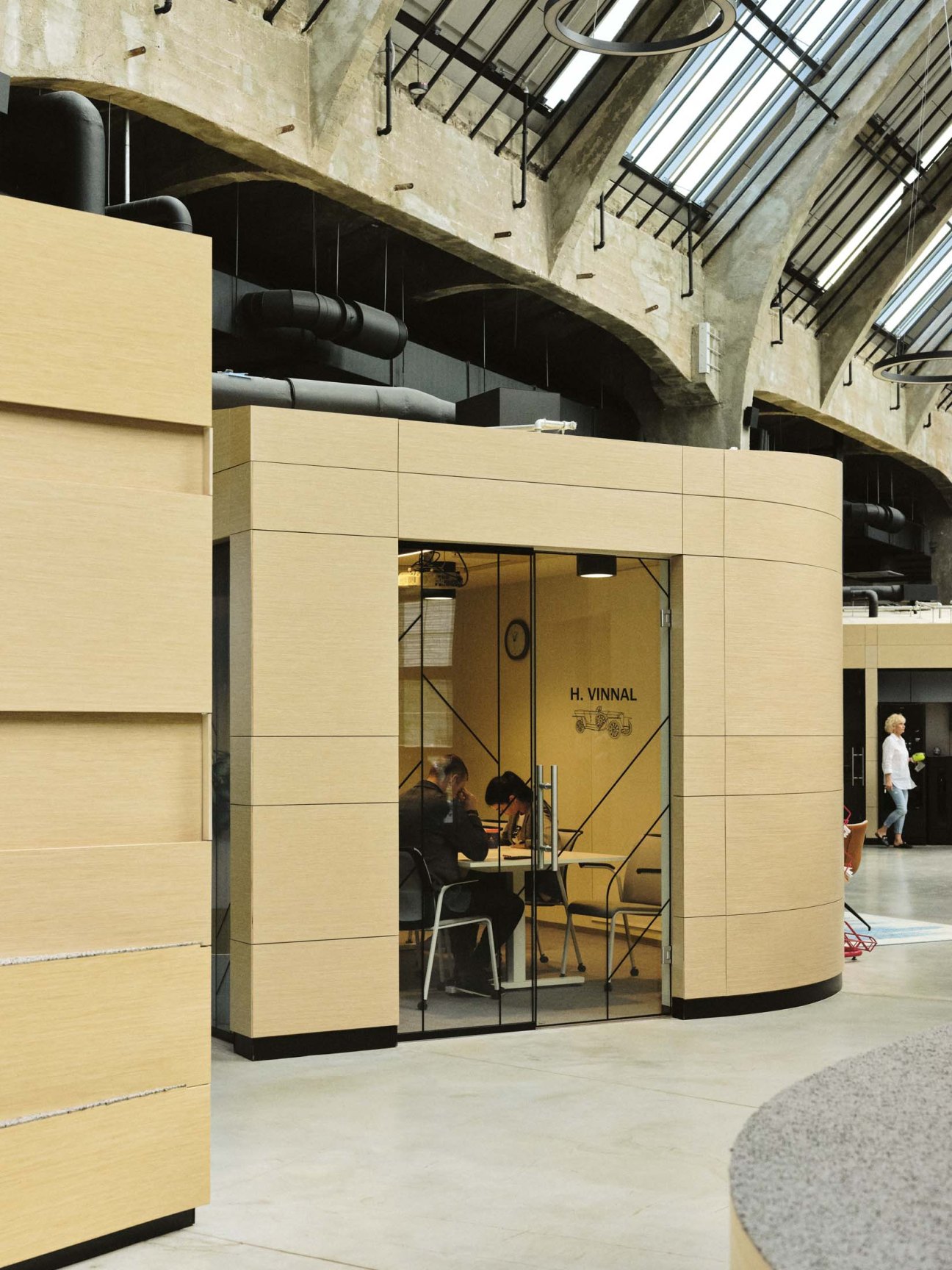 Plywood-clad meeting room with glass door in an industrial office space